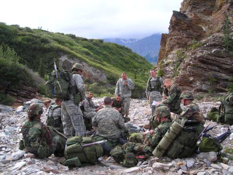 2003 Jeep TJ - Soldiers are gathered in a rocky, mountainous terrain, possibly during a break or briefing.