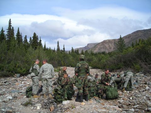 2003 Jeep TJ - A group of soldiers takes a break in a , natural landscape with trees and mountains.