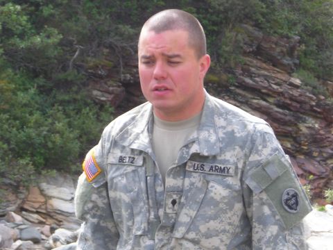 2003 Jeep TJ - A U.S. Army soldier stands outdoors with a rocky, vegetated background. His uniform has name and service tapes.