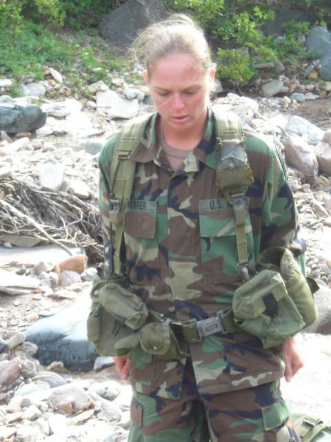 2003 Jeep TJ - A person in military uniform with tactical gear stands in a rocky, outdoor environment.