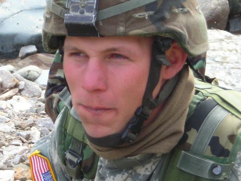 2003 Jeep TJ - A close-up of a soldier in military gear, with a rocky landscape behind them.