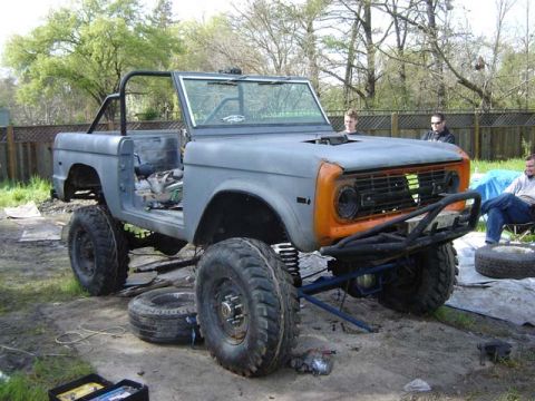 1974 Ford F-100 - This modified Ford Bronco, likely from the 1970s, is in a state of disrepair with its doors removed and large off-road tires fitted.