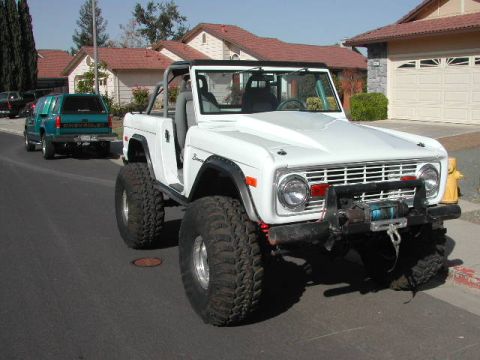 1974 Ford F-100 - Modified white Ford Bronco with off-road tires and a front winch is parked on a street.