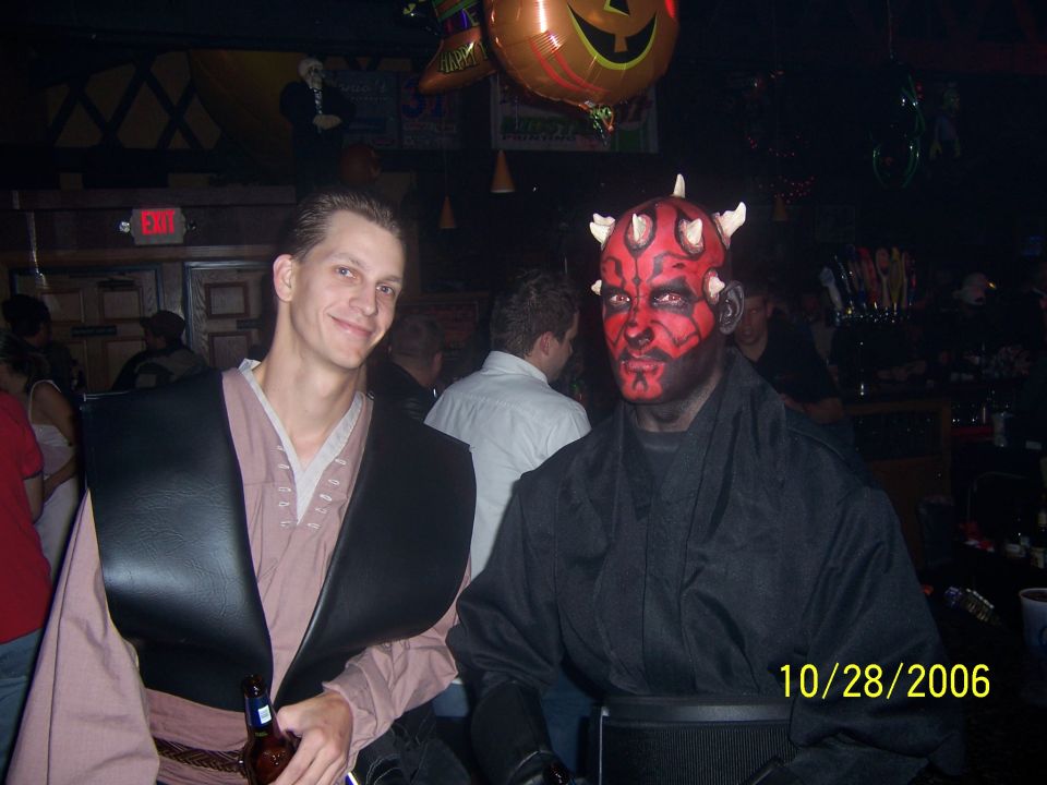Two guys in costumes, one dressed as Darth Maul, at a bar with a Halloween balloon