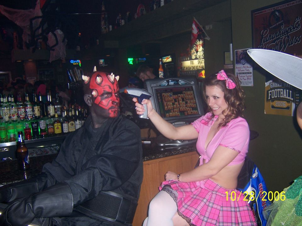 Person in Darth Maul costume and person in pink outfit with toy gun at a bar