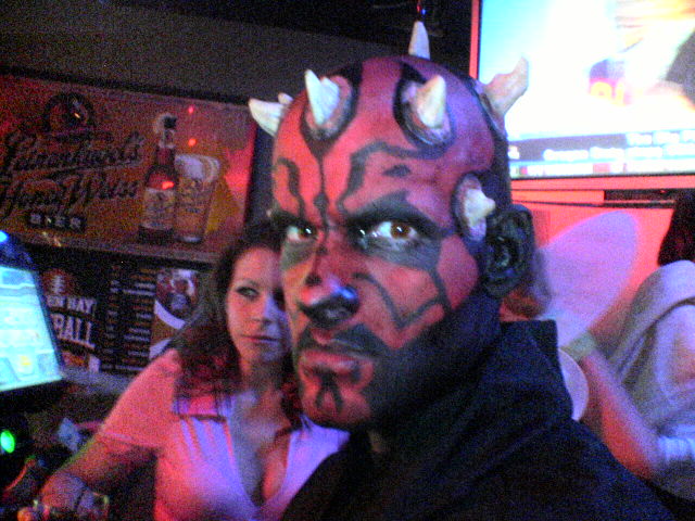 Person in Darth Maul costume with face paint and horns, with a woman in a pink shirt behind them