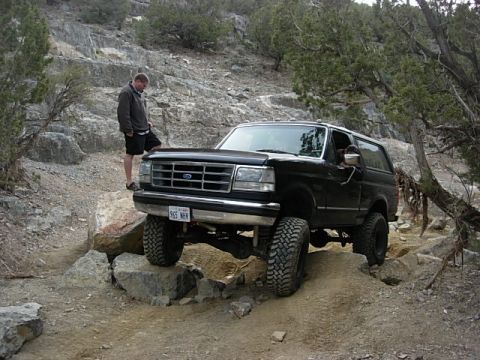 1987 Ford Bronco - Black 1987 Ford Bronco tackling rough terrain on a sunny day.