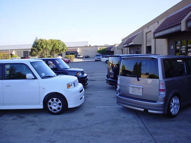 White and silver SUVs parked in a lot with a building in the background