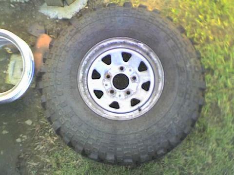 1989 Ford Bronco - Close-up of an off-road tire and rim, with a second rim partially visible.