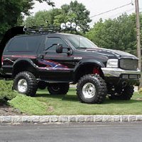 1995 Ford Bronco - Lifted black Ford Bronco with custom graphics and roof rack, parked on grass.