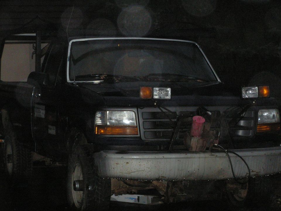 Black 1992 Ford F-250 truck front view, with aftermarket lights and a damaged bumper
