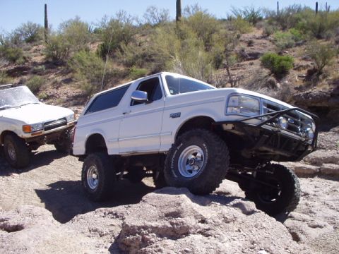 1993 Ford Bronco - Modified 1993 Ford Bronco and another SUV off-roading in a desert environment.