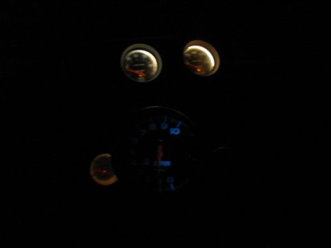 1985 Ford Crown Victoria LTD - Illuminated dashboard gauges are visible in the dark interior of a vehicle.