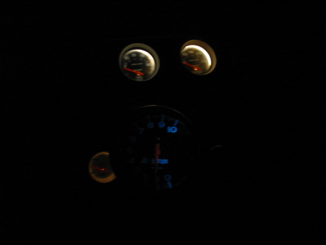Dashboard gauges illuminated at night with blue and yellow lighting