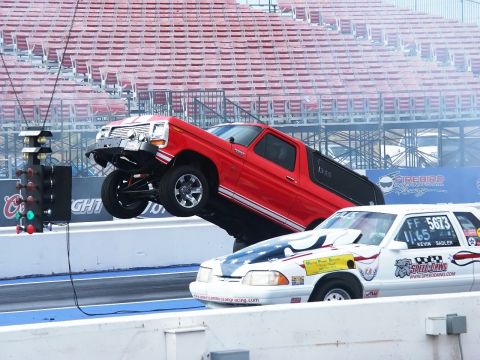 1979 Ford Bronco - A red Ford Bronco launches off the line, its front wheels lifting dramatically during a drag race.