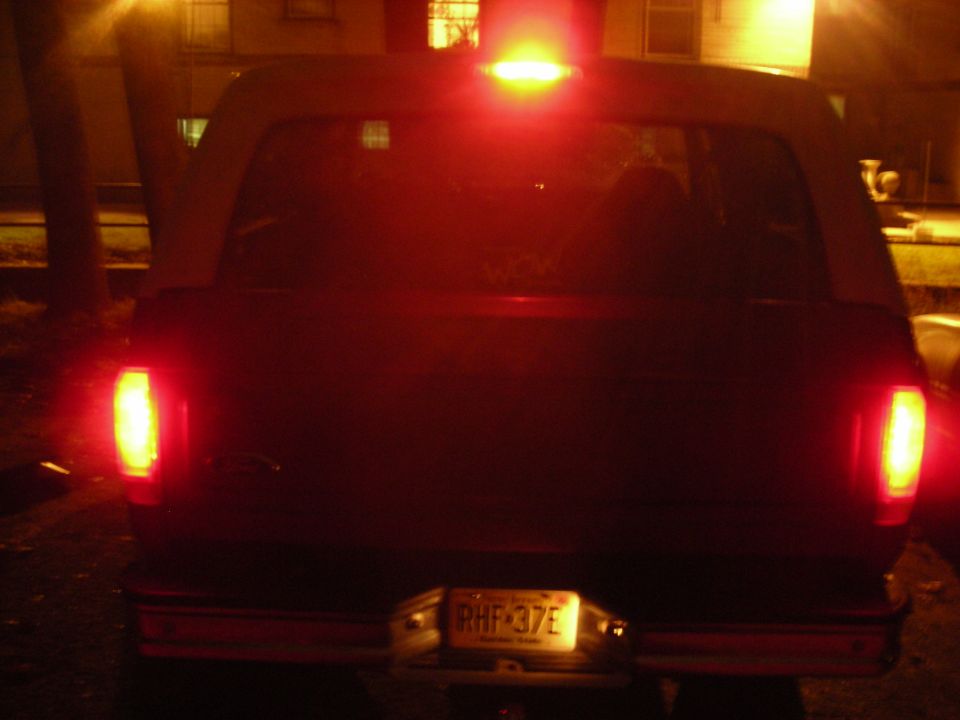 Rear view of a dark SUV with illuminated brake lights and license plate RHF-37E