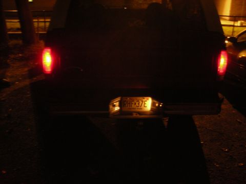 1995 Ford Bronco - The rear of a pickup truck is shown at night, with its taillights illuminated.