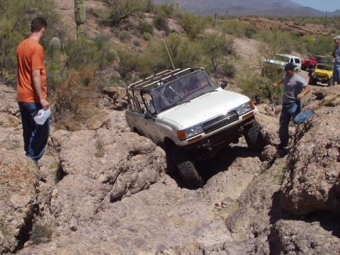 1993 Ford Bronco - Off-roading in the desert with multiple vehicles navigating challenging rocky terrain.