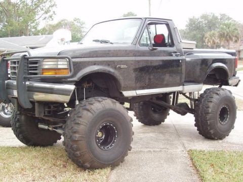 1974 Ford F-100 - This modified pickup truck features oversized tires and a raised suspension system, suggesting off-road capability.