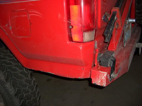 1985 Ford Bronco - Rear view of a red truck, likely from the 1980s, with visible damage to the bumper and body.