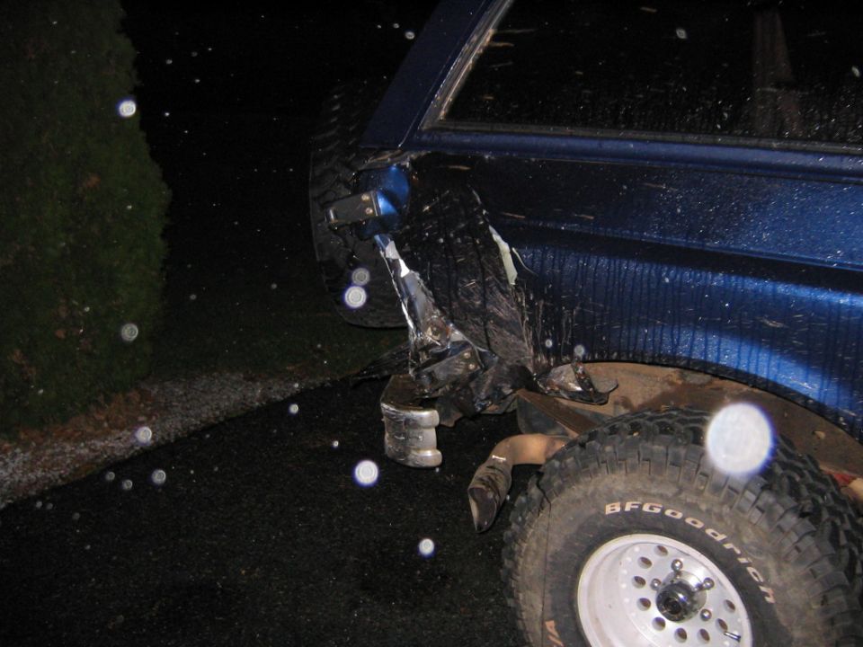 Torn rear quarter and displaced BFGoodrich tire on a blue lifted Ford, night flash photo