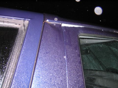 1994 Ford Bronco - Close-up view of a damaged purple vehicle door frame, showing signs of wear and tear.