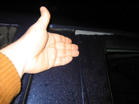 1994 Ford Bronco - A hand is used to show the size of a gap on a dark blue vehicle's door panel.