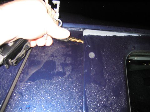 1994 Ford Bronco - A hand holds a set of keys near the seam of a car door, possibly about to unlock it.