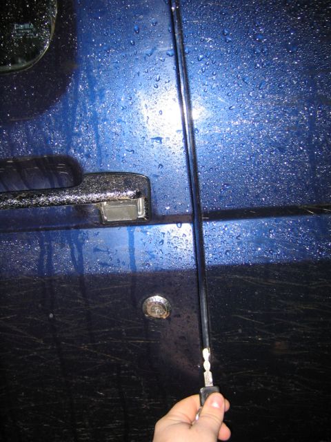 1994 Ford Bronco - Close-up of a blue vehicle door, showing the chrome handle and an antenna with a hand holding a key.