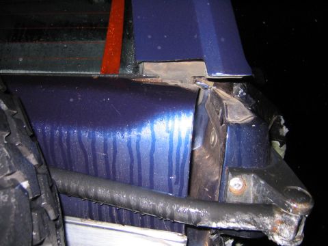 1994 Ford Bronco - The rear quarter panel of a blue 1994 Ford Bronco shows significant damage.