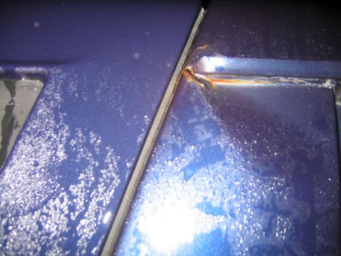1994 Ford Bronco - Rust is visible along the seam of a blue vehicle's body panels.