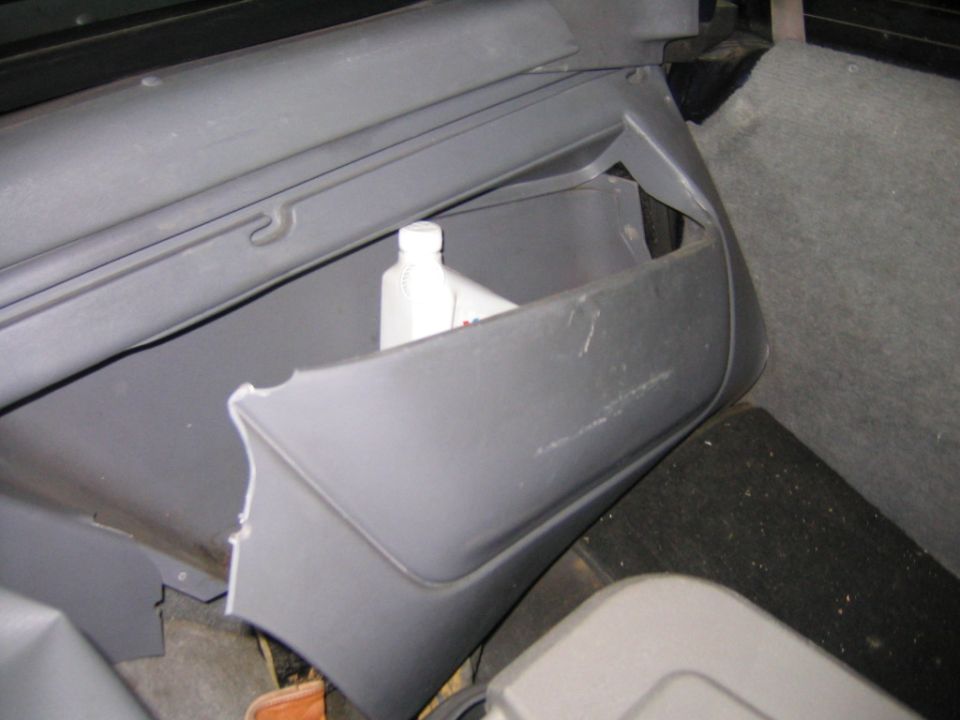 Cracked gray rear quarter trim panel inside an SUV, storage pocket broken