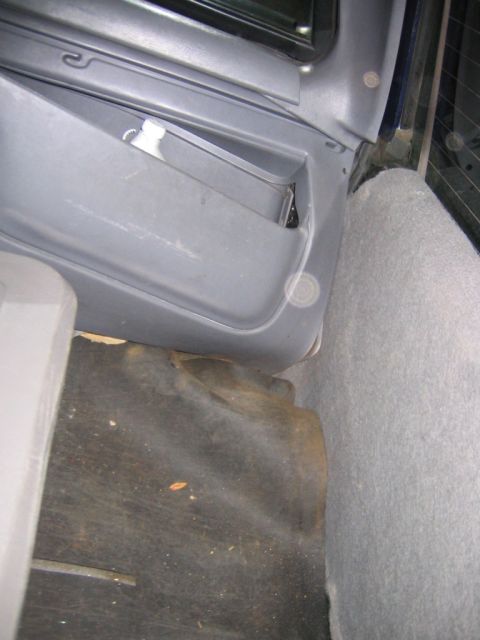 1994 Ford Bronco - The interior cargo area shows a storage compartment and worn carpeting.