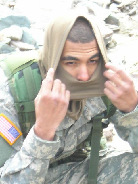 2003 Jeep TJ - A soldier adjusts their headwear while wearing a camouflage uniform and a US flag patch on their arm.