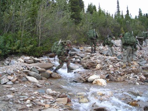 2003 Jeep TJ - Military personnel navigate a challenging stream crossing during a training exercise in a , natural environment.
