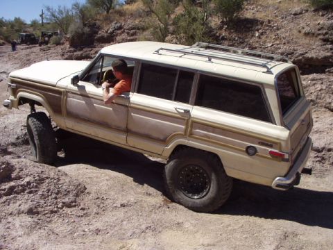 1993 Ford Bronco - Jeep Grand Wagoneer navigating a rocky off-road trail with another vehicle in the distance.