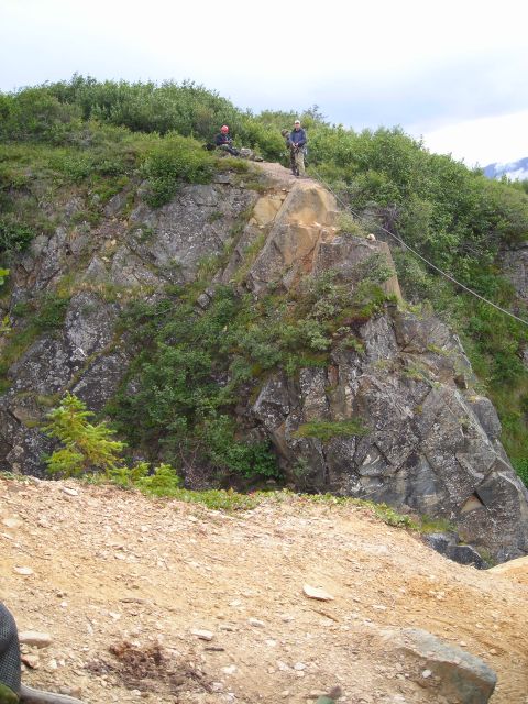 2003 Jeep TJ - Two individuals are positioned on a , vegetated cliff face with a cable extending across the landscape.