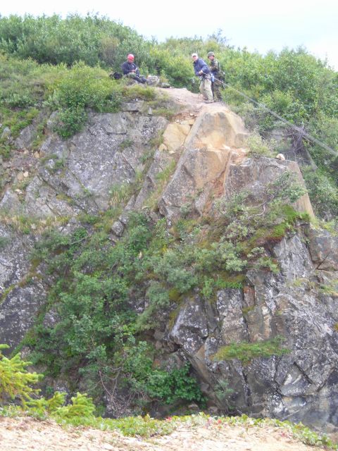 2003 Jeep TJ - People are gathered on a rocky outcrop, with vegetation growing on the cliffside.
