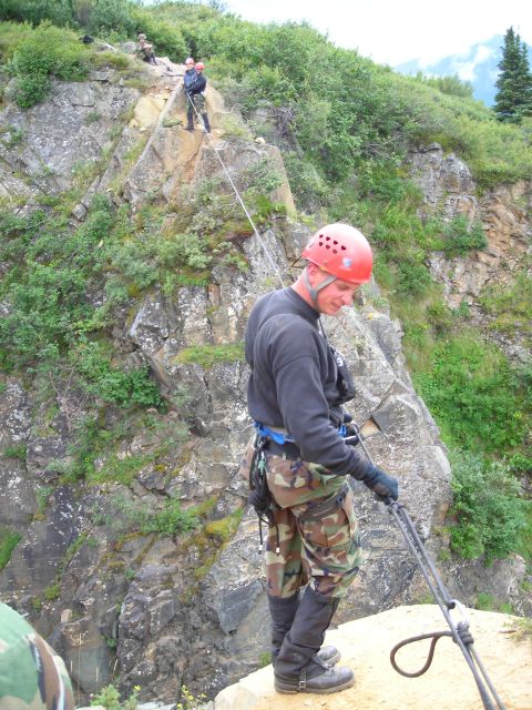 2003 Jeep TJ - Several individuals are engaged in rappelling down a , rocky incline with ropes and safety gear.