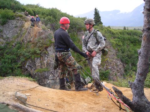 2003 Jeep TJ - Military personnel practice rappelling on a steep, vegetated mountainside under a cloudy sky.
