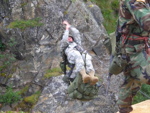 2003 Jeep TJ - Two soldiers in camouflage gear are engaged in a rappelling exercise down a steep, rocky incline.