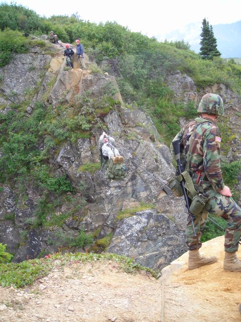 2003 Jeep TJ - Soldiers participate in a rappelling exercise on a steep, rocky mountainside, with one soldier observing from the edge.
