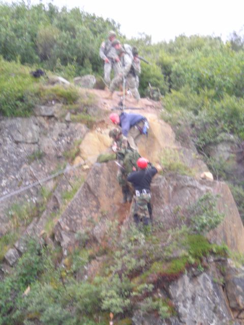 2003 Jeep TJ - Military personnel are engaged in a rappelling exercise down a , vegetated cliff face.