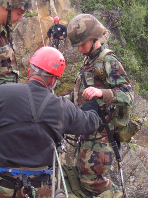 2003 Jeep TJ - Soldiers are seen in camouflage uniforms and helmets, with one assisting another with rappelling gear on a steep, rocky incline.