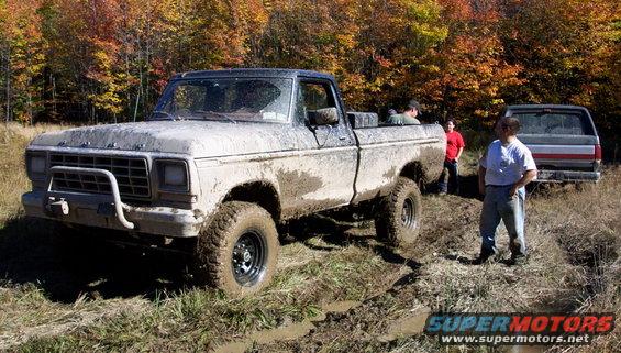 Mud-covered 1979 Ford F-250 with a brush guard, seen from the front-left in a muddy field