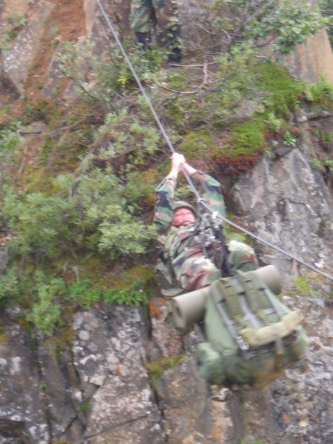 2003 Jeep TJ - Soldiers descend a steep, rocky incline using a rope system, equipped with full gear and backpacks.