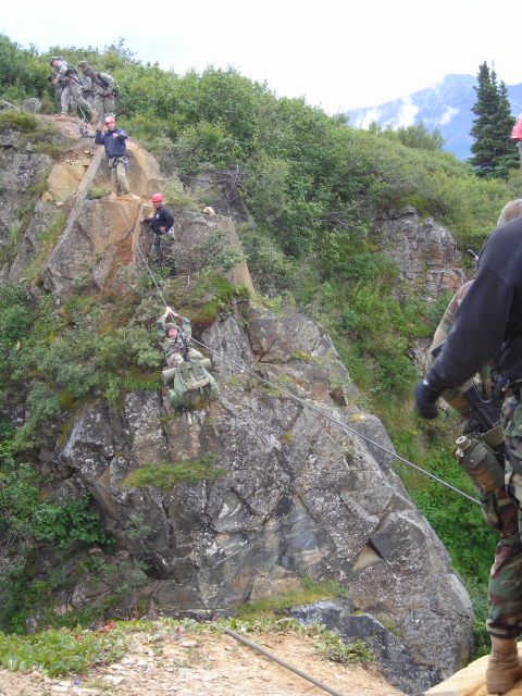 2003 Jeep TJ - Military personnel are engaged in a rappelling exercise on a , vegetated cliff face.