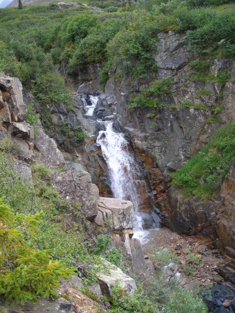 2003 Jeep TJ - A waterfall flows down a , rocky mountainside covered in green vegetation.