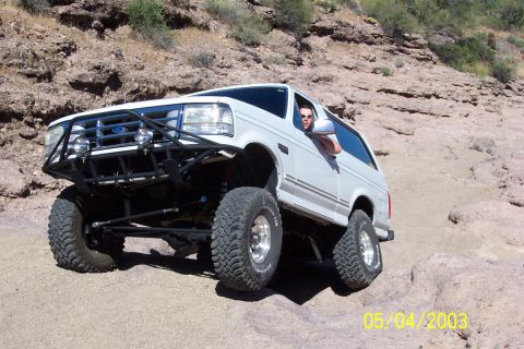 1993 Ford Bronco - White Ford Bronco navigating a rocky off-road trail.