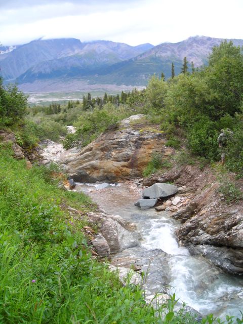 2003 Jeep TJ - A scenic view of a mountain valley, a stream and lush vegetation under a cloudy sky.